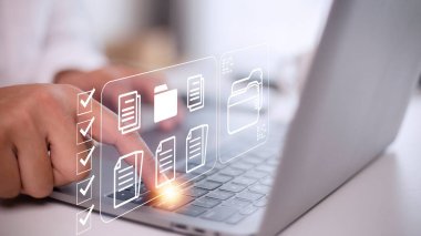 Document Management System (DMS) being setup by IT consultant working on laptop computer in office. Software for archiving, searching and managing corporate files and information
