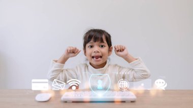 Çocuk güvenliği devrede. Evde dizüstü bilgisayar kullanan küçük bir kız. Önplanda internet engelleme uygulamasının simgesi