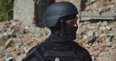Mahvolmuş bir evin arka planında silahı olan bir Ukraynalı asker.