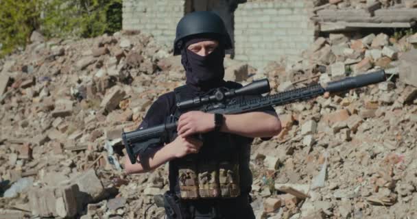 Солдат з гвинтівкою дивиться на тлі зруйнованого будинку — стокове відео