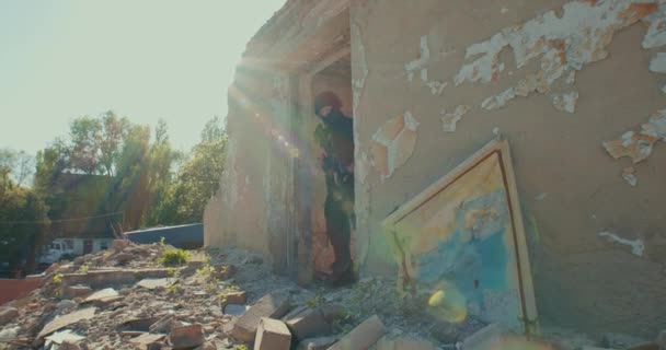 A soldier with a weapon comes out of a destroyed house — Wideo stockowe