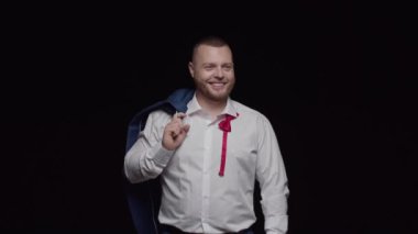 Beyaz gömlekli, düğmesiz kırmızı kravatlı ve omuzunda ceketi olan seksi bir adam içtenlikle gülüyor..