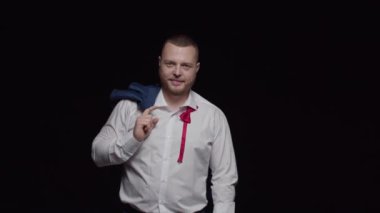 Beyaz gömlekli, düğmesiz papyonlu ve omuzlarının üzerinden attığı ceketli bir adam gülümsüyor..