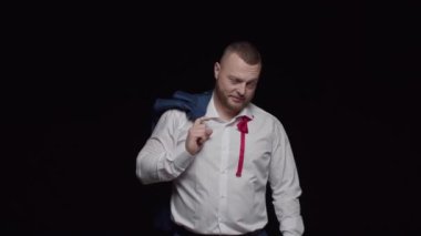 Kırmızı papyonlu, beyaz gömlekli, düğmeleri iliklenmemiş ve omuzuna montlu bir adam baştan çıkarıcı bir şekilde ileriye bakıyor..