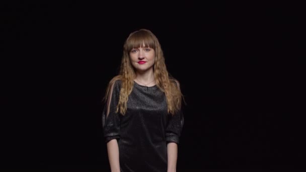 Молода спокуслива жінка в темній сукні позує себе на чорному тлі, моді та гламурності — стокове відео