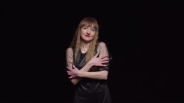 Koyu renk elbiseli, baştan çıkarıcı genç bir kadın siyah arka plan, moda ve cazibe üzerine poz veriyor..