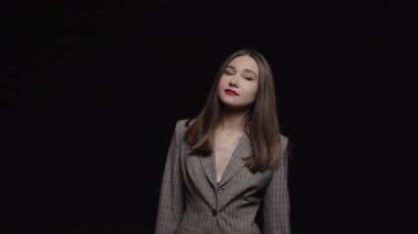 Pejak 'teki güzel bir kız kameraya bakar ve siyah bir arka planda sallanır..