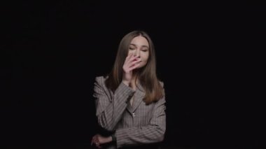 Ceketli genç ve güzel bir esmer siyah arka planda baştan çıkarıcı bir şekilde kameraya bakar..