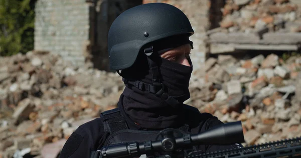Mahvolmuş bir evin arka planında silahı olan bir Ukraynalı asker. Yakın plan..