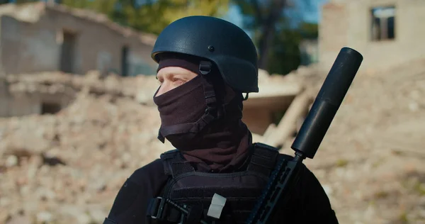 Askeri üniformalı silahlı bir asker kafasını çevirir ve önüne bakar. Yakın plan..
