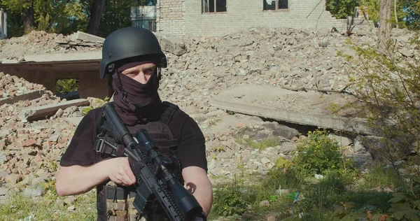 Bir Ukraynalı asker yıkılmış bir evin zeminine ateş ediyor. Orta boy..