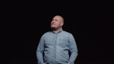 Kel ve sakallı bir adam dikkatlice en tepeye bakar ve sonra kameraya bakar..