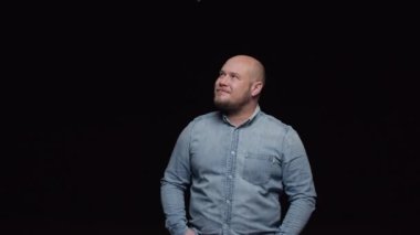 Sakallı kel bir adam etrafına bakıyor ve kafasını olumlu bir şekilde sallıyor..