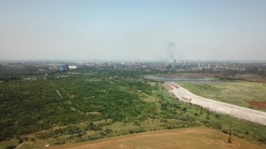 Ekolojiyi borulardan gelen dumanla kirleten bir bitkinin yakınındaki buğday tarlasında yüksek uçuş.
