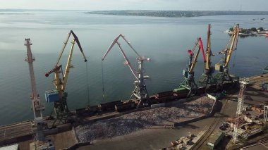 Limanın sanayi bölgesinde metal yük vinçleri için terminaller. Vagonlardan dökme demir. Lojistik endüstrisi, nakliye işi konsepti. İHA yüksek açı görüntüsü taraması.