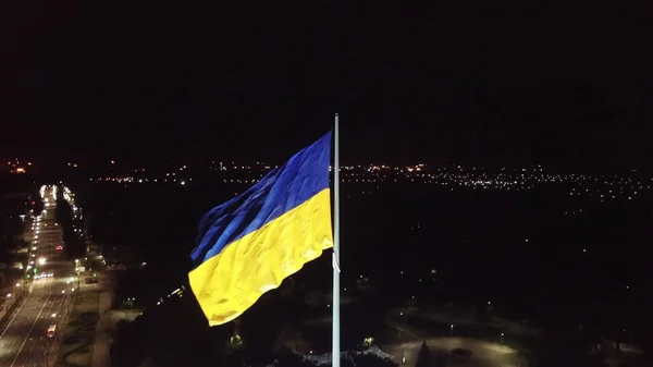 Hava görüntüsü. Ukrayna bayrağı geceleyin rüzgârda dalgalanır. İHA yüksek açı görüntüsü taraması