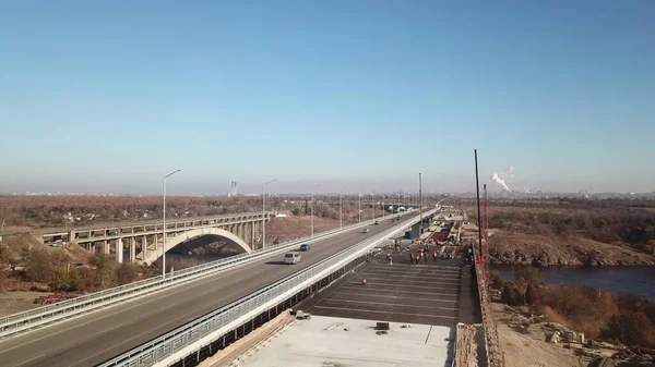 Nehir üzerinde bir köprü inşaatı. Köprüde otomobil trafiği. Yukarıdan bak. İHA yüksek açı görüntüsü taraması.