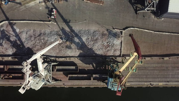 Aerial view. Unloading of cast iron from vogons in the seaport. Logistic industry, freight transportation business concept. Drone aerial high angle view panning