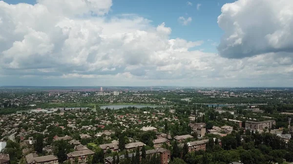 Güneşli bir yaz gününde endüstriyel bir şehir. Şehrin üzerinde büyük blokları olan mavi bir gökyüzü. İHA yüksek açı görüntüsü taraması.