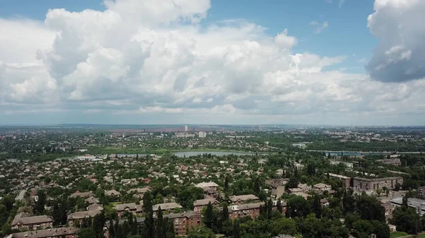 Yağmurdan sonra güneşli bir yaz gününde endüstriyel bir şehir. Şehrin üzerinde büyük blokları olan mavi bir gökyüzü. İHA yüksek açı görüntüsü taraması.
