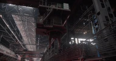 Pençeleriyle vinç, kırmızıya ısıtılmış çelik bir külçeyi kaldırıyor. Çelik koğuş üretimi. Metalürjik bitki. Yuvarlanan dükkan. İş konsepti, modern çelik üretim teknolojisi.