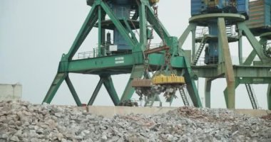 Bir kargo manyetik vinci dökme demiri iskeleye boşaltıyor. İş kavramı, deniz yoluyla ulaşım lojistiği. Ticari Deniz Limanı. Deniz yoluyla teslimat..