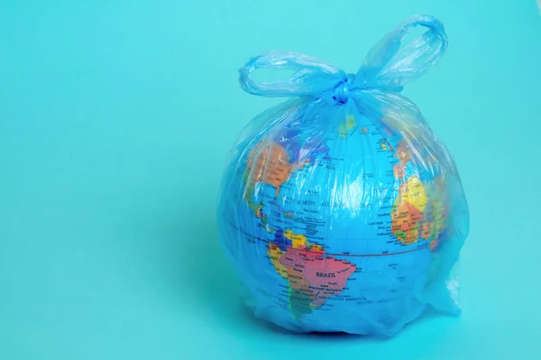 Planet Earth in a plastic bag on a blue background. Africa sorting garbage. Cleansing the world\'s oceans. Copy space. Concept