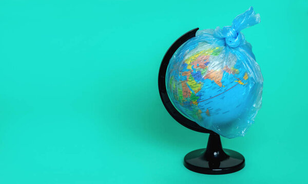Globe in a plastic bag on a blue background. Global warming. Waste sorting. Cleansing and protecting the planet. Copy space. Concept
