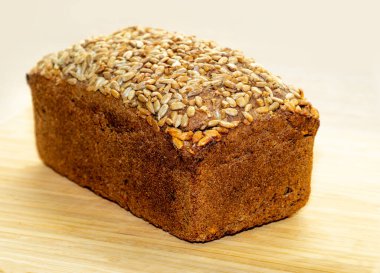 Dikdörtgen ekmek. Tahta bir masada ayçiçeği tohumlu siyah çavdar ekmeği..