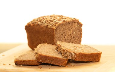 Dilimlenmiş çavdar ekmeği ve ahşap bir masada ayçiçeği tohumları..