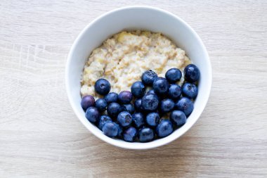 Tahta bir masada yulaf ezmesi ve yaban mersinli tabak. Evde pişir..