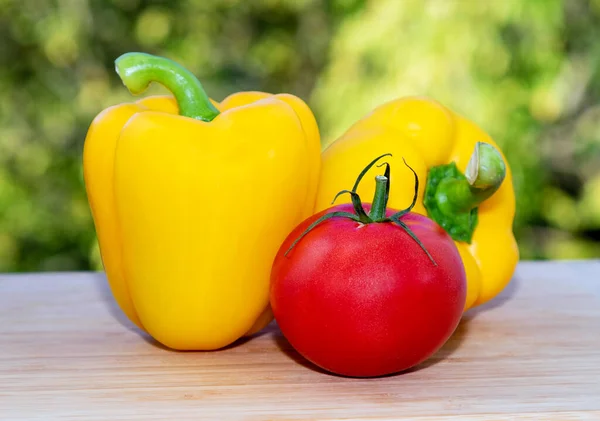 Two yellow peppers and a red tomato. Vegetables from the farmers fresh harvest.