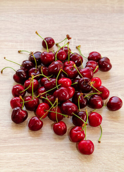 Ripe red cherries on a wooden table. vertical photo,