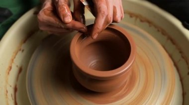 Çömlekçi elleri çömlekçi çarkının kenarındaki sürahinin kenarını oluşturur, yakın plan.