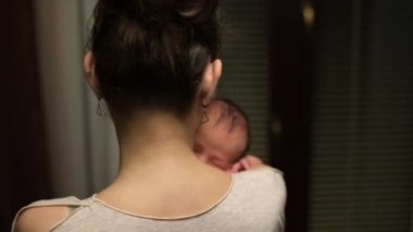 Genç bir kadın yeni doğmuş bir bebeği omuzunda tutuyor. Anne ve çocuk.