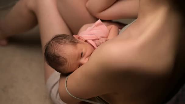 The camera zooms in and shows a close-up of a newborn baby being milked — 图库视频影像