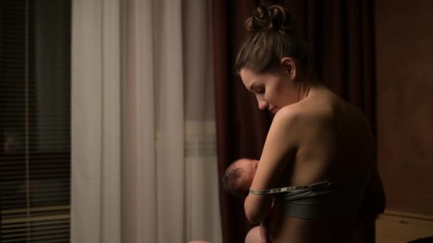 Jovem mãe amamenta seu bebê e vira o rosto para a câmera em casa — Vídeo de Stock