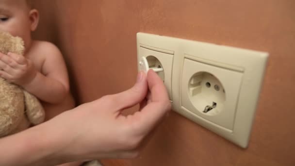 A young mother carefully plugs power outlets with special plugs — Stok video