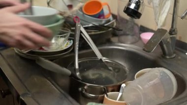 Dirty dishes are put in the sink, which already contains many dirty dishes