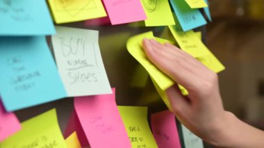 A woman puts a sticker with a to-do list and a shopping list on the refrigerator