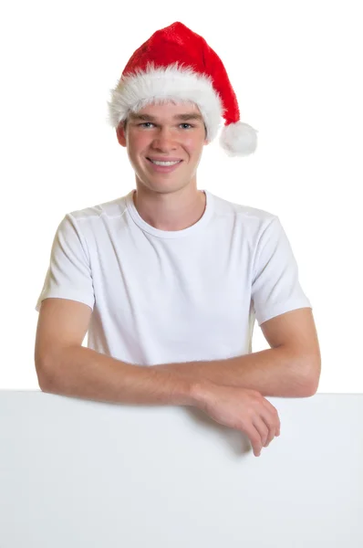 Attractive guy with christmas hat on a blank sign — Stock Photo, Image