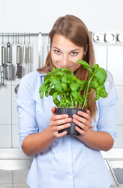 Mujer joven oliendo a albahaca fresca — Foto de Stock