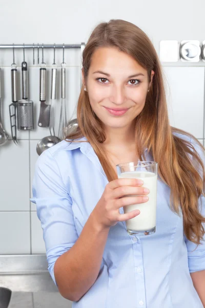 Mujer sonriente en la cocina bebiendo leche — Foto de Stock