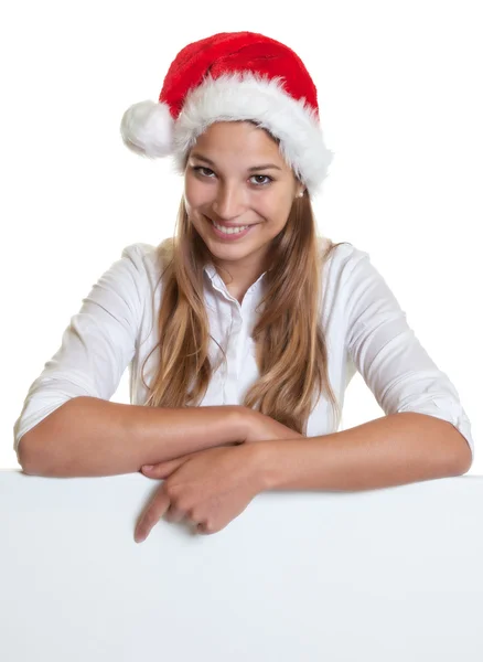 Young woman with christmas hat pointing on a signboard — Stock Photo, Image