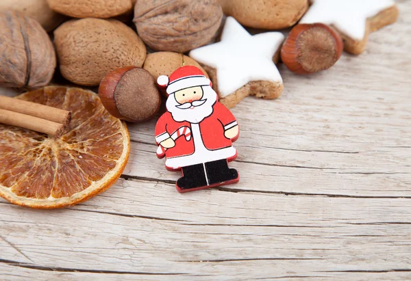 Papai Noel com nozes, laranjas e biscoitos na borda da madeira — Fotografia de Stock