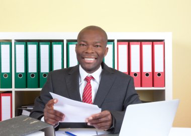 Laughing african businessman reading a letter clipart