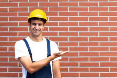 Presenting young worker in front of a brick wall clipart