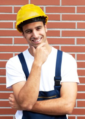 Friendly smiling worker in front of a brick wall clipart