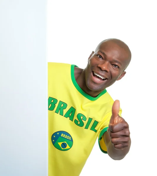 Abanico de fútbol brasileño detrás de un letrero en blanco mostrando pulgar — Foto de Stock