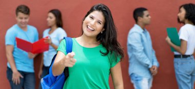 Kolej kampüsünde çok ırklı genç yetişkinlerle birlikte heyecanlı bir beyaz kız öğrenci.